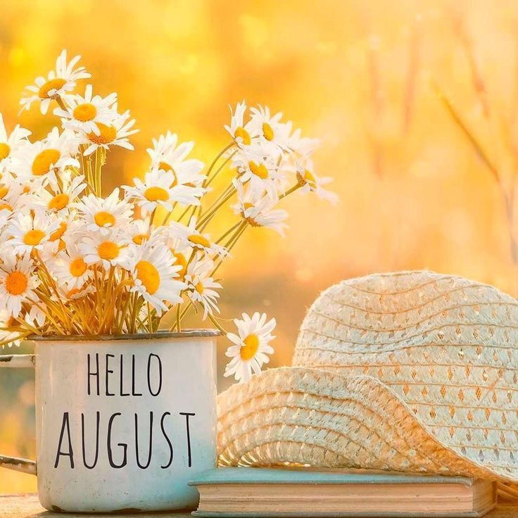 a hat and flowers are sitting on a table next to a mug with the words hello august