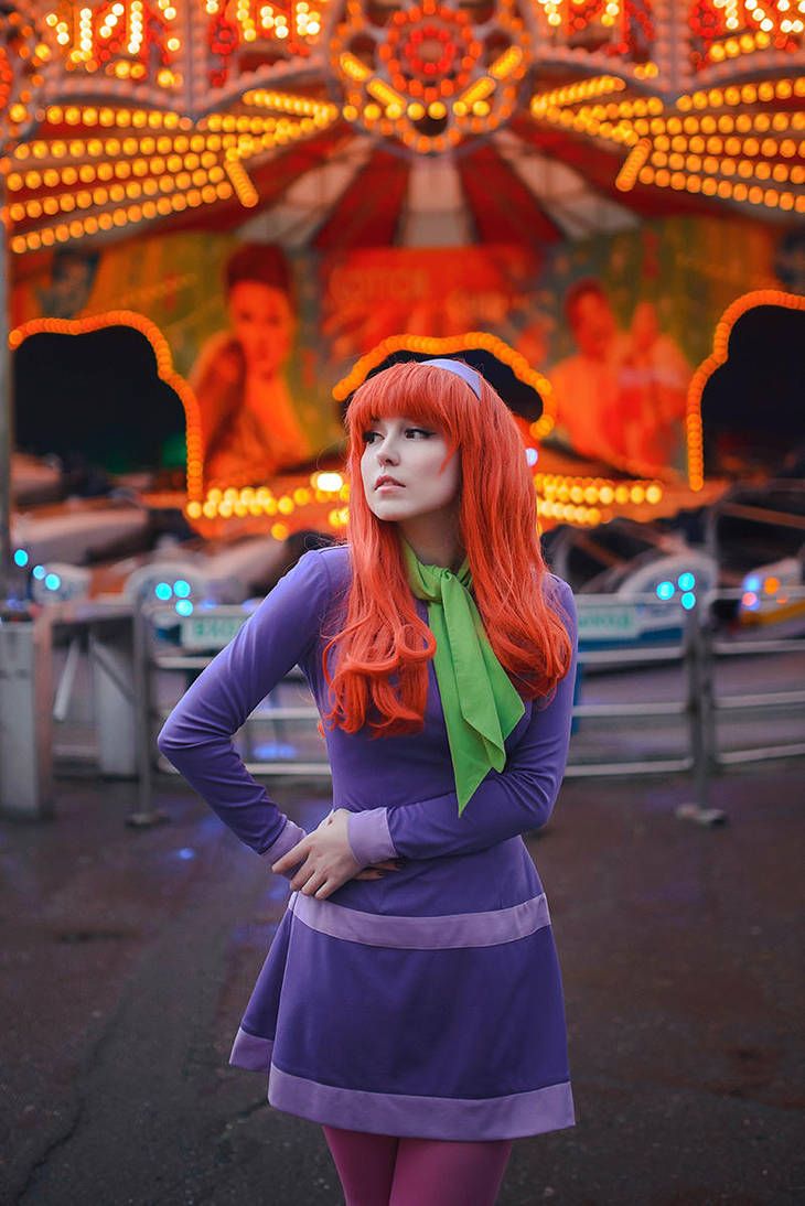 a woman with red hair standing in front of a carnival ride