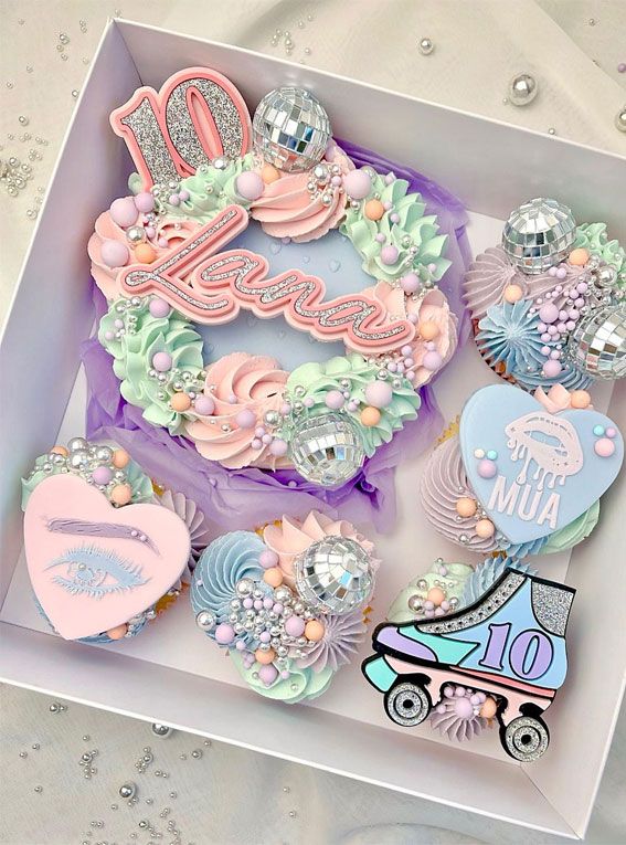 a box filled with cupcakes covered in frosting and decorative decorations on top of a table