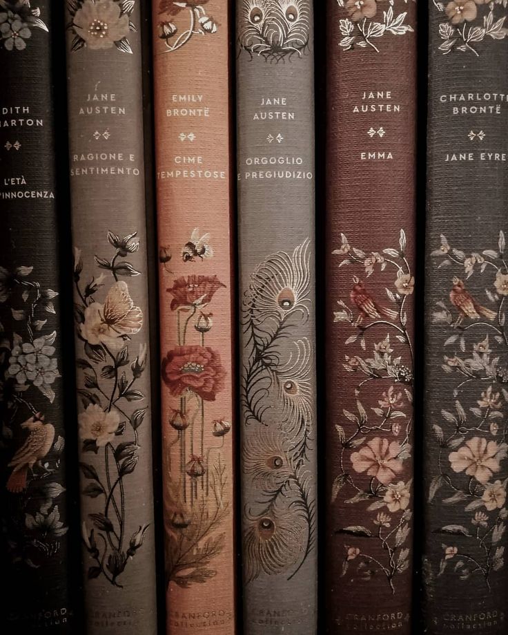 four books are lined up in rows on a shelf with flowers and leaves painted on them