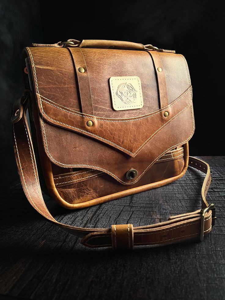 The Quinn. A messenger style, rugged, and roomy shoulder bag.  Made with fine quality, full grain Bison leather, and featuring an internal zippered pocket system.  High quality, solid brass turn lock on the front.  Adjustable, heavy duty shoulder strap.  Unique design: its name derived from that of its creator's (my middle name). Everyday Flap Shoulder Bag With Brass Hardware, Everyday Leather Backed Satchel, Bridle Leather Satchel Shoulder Bag With Leather Backing, Leather Flap Bag With Brass Hardware, Leather Flap Bag With Brass Hardware For Everyday Use, Oiled Leather Satchel Shoulder Bag With Leather Lining, Classic Bags With Leather Strap For Everyday Carry, Satchel Saddle Bag With Brass Hardware For Everyday Use, Rugged Rectangular Shoulder Bag For Everyday Carry