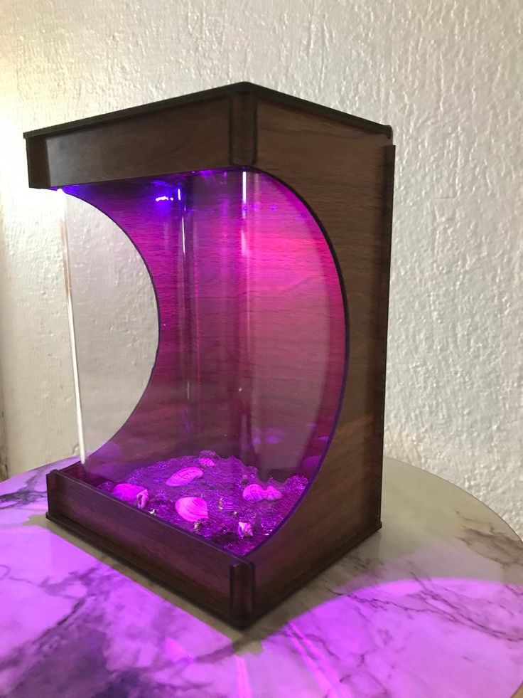 a purple and black fish tank sitting on top of a marble table next to a white wall