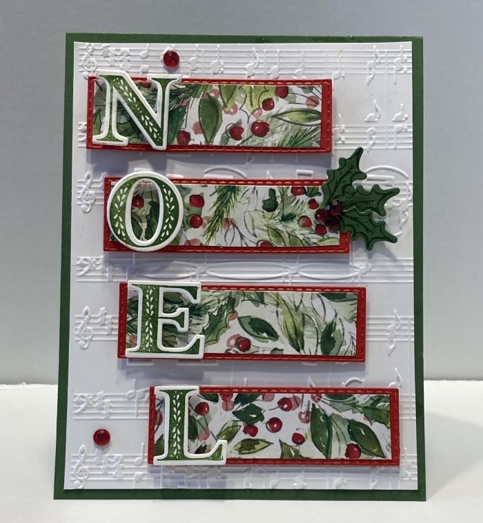 a christmas card with the word noel written in red and green letters, holly leaves and mist