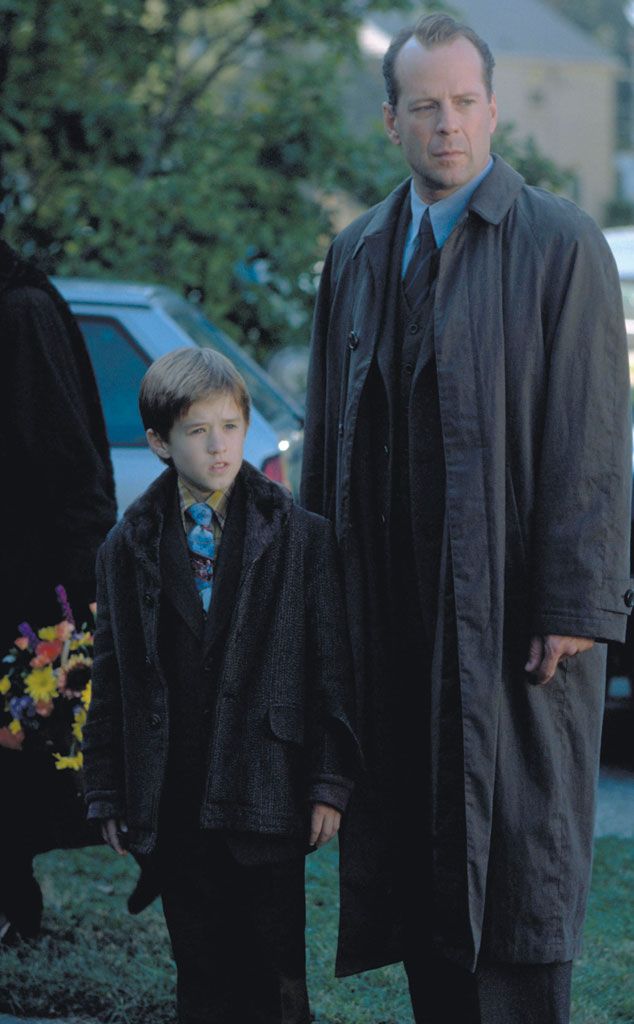 a man standing next to a little boy in a suit and tie on the street