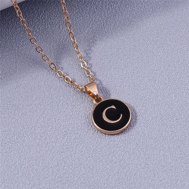 This elegant 26-letter pendant necklace is crafted with A-Z letters for a personalized look. The gold color and black enamel background make it a perfect addition to any ensemble. An ideal gift for any special occasion, this necklace lets you customize it with the initial of your choice. Trendy Personalized Black Necklace, Trendy Black Personalized Necklace, Elegant Gold Necklaces With Letter Print, Elegant Gold Necklace With Letter Print, Trendy Black Jewelry With Letter Print, Black Pendant Jewelry For Personalized Gift, Black Pendant Necklace For Personalized Gift, Personalized Black Pendant Jewelry, Personalized Black Pendant Necklace