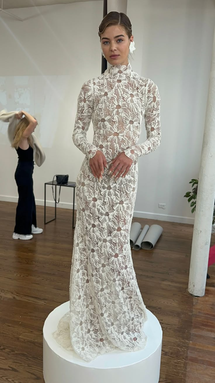 a woman standing in front of a white sculpture with her hands on her hips and looking at the camera