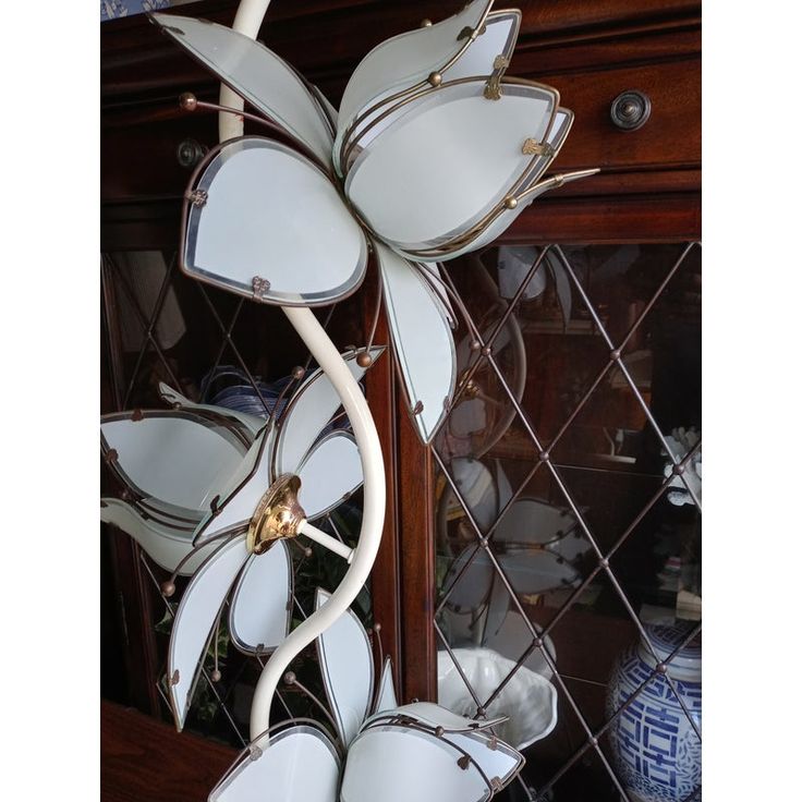 a white flower shaped vase sitting on top of a wooden table next to a mirror