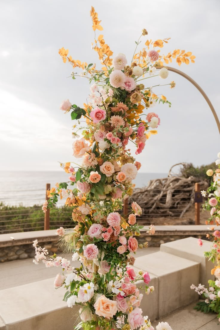 an outdoor wedding ceremony with flowers and greenery on the aisle, overlooking the ocean