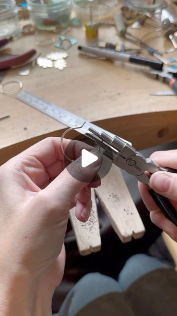 a person is holding a pair of scissors in front of a table full of tools