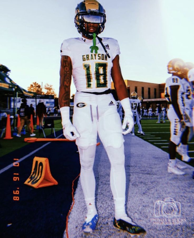 a football player is standing on the sidelines with his uniform and helmet in hand