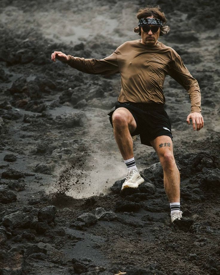 a man kicking a soccer ball in the mud