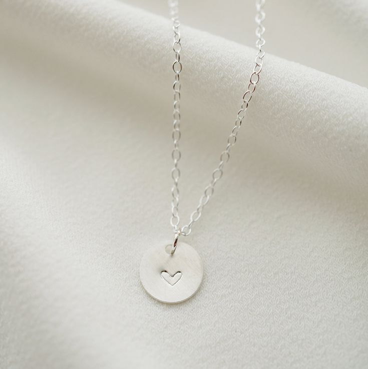 "A dainty silver coin is delicately suspended on a sterling silver necklace chain, and hand stamped with an uppercase letter of your choice. Add on additional coins personalized with letters of your choice, or a heart symbol. Hand stamped to order in our Vancouver studio. *Free shipping for orders to USA and Canada, and no duties or customs fees.* > Sterling silver coin is 9mm in diameter > Shown worn on a 16\" satellite chain > Comes beautifully packaged and ready for gift giving > Simple Hand Stamped Necklace As Gift, Dainty Hand Stamped Charm Necklace For Anniversary, Dainty Hand-stamped Charm Necklace For Anniversary, Dainty Hand Stamped Necklaces For Anniversary, Hand Stamped Minimalist Pendant Necklace, Anniversary Dainty Hand-stamped Charm Necklace, Minimalist Hand Stamped Pendant Necklace, Dainty Hand Stamped Charm Necklaces For Everyday, Simple Personalized Charm Necklace As Gift For Her