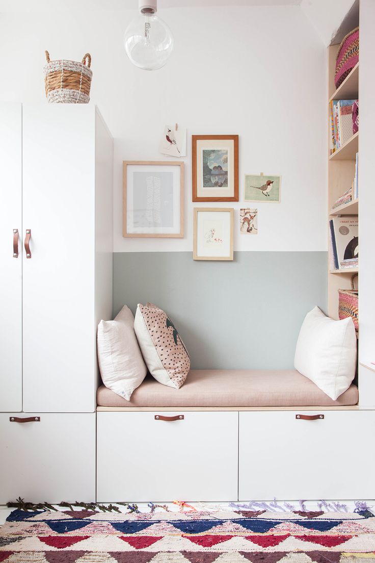 a room with some white cabinets and pictures on the wall above it, along with pillows