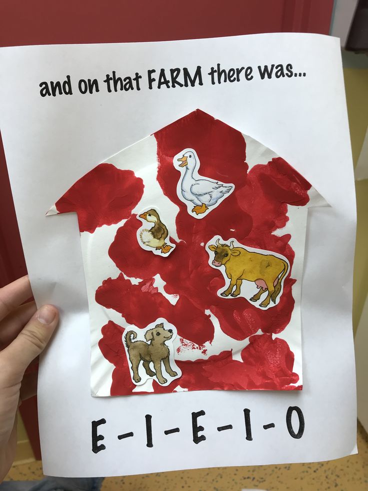 a child's hand holding up a piece of paper with farm animals on it