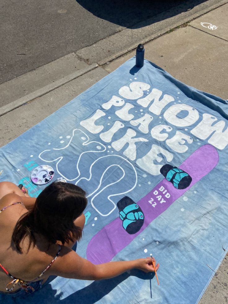 a woman is painting on the sidewalk with her skateboard and other things in front of her