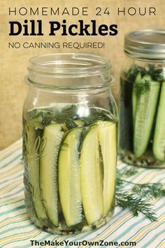 two jars filled with pickles sitting on top of a striped table cloth next to each other