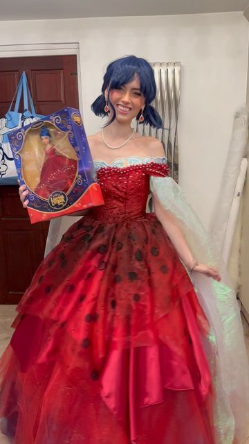 a woman in a red and black dress is holding up a box with an image on it