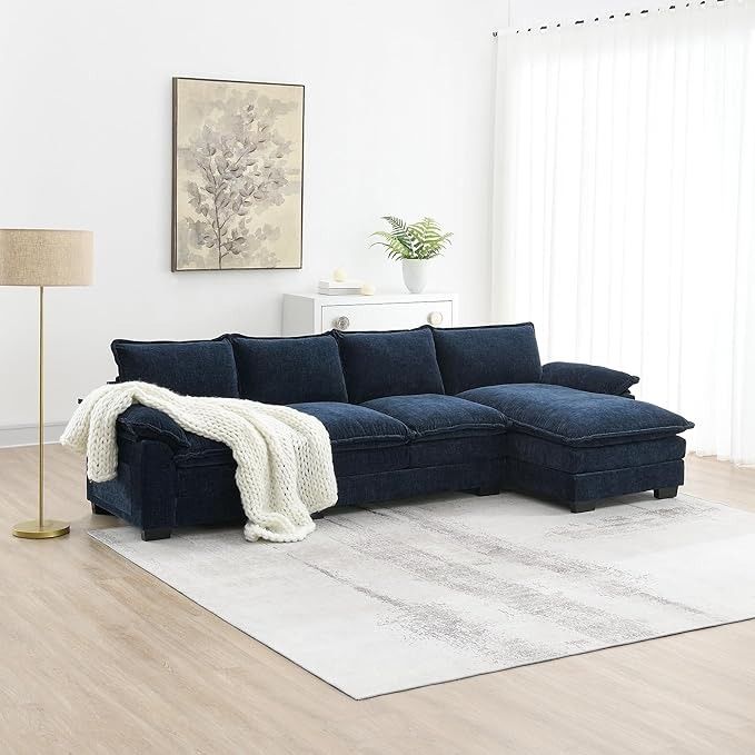 a living room with a blue sectional couch and white rugs on the hardwood floor