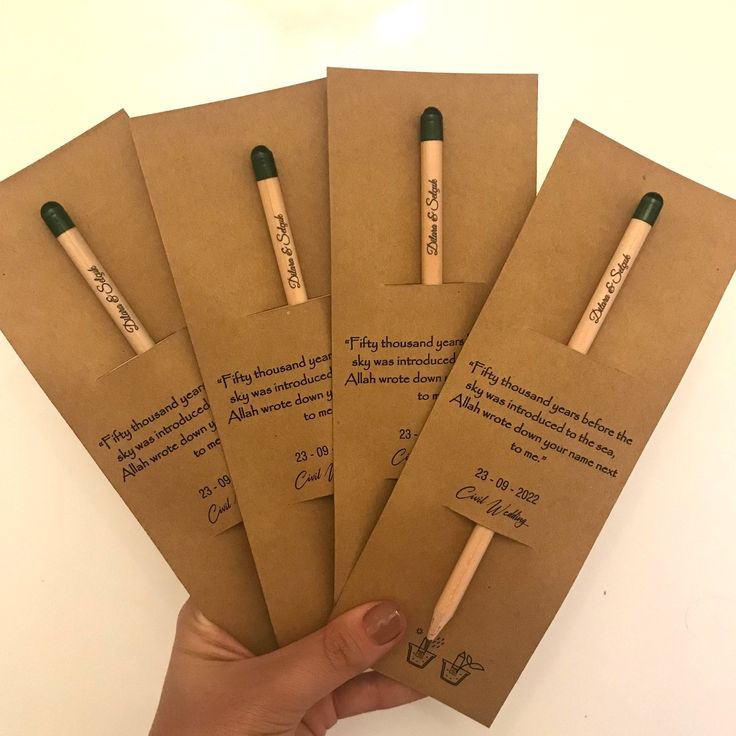 four brown envelopes with writing on them are held by a person's hand