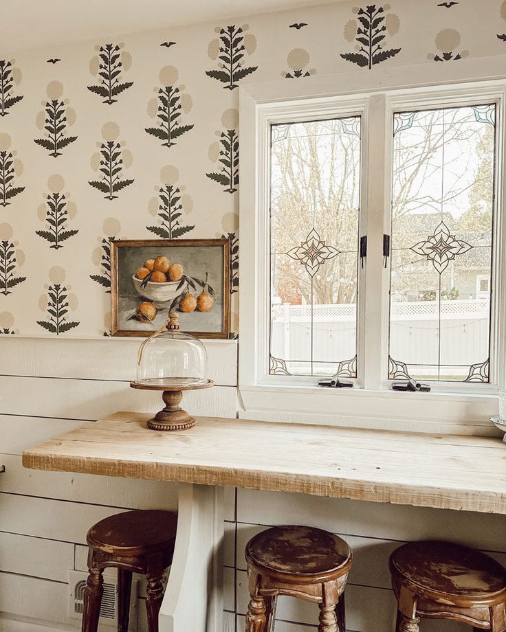 a kitchen counter with two stools next to it and a wallpapered background