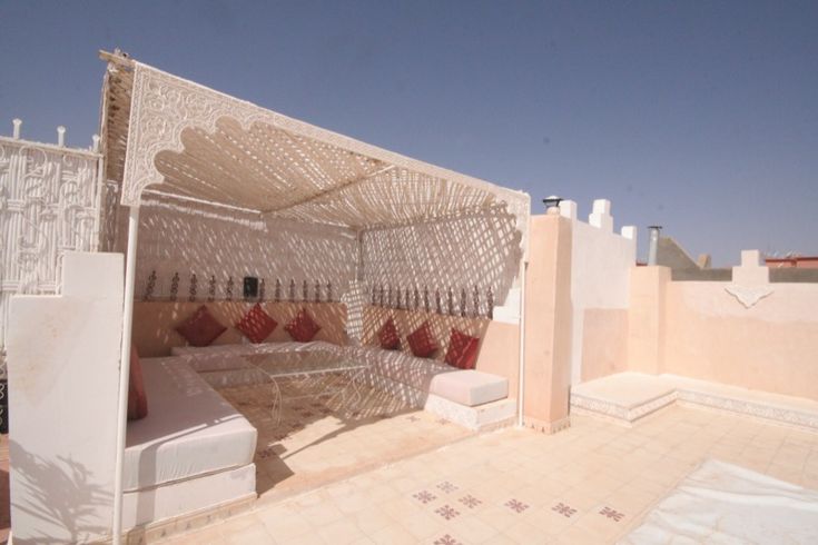 an outdoor seating area on the roof of a building with white walls and tile floors