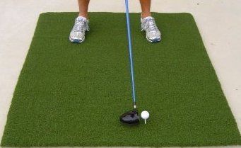 a man is playing golf on the green mat with his foot in the air,