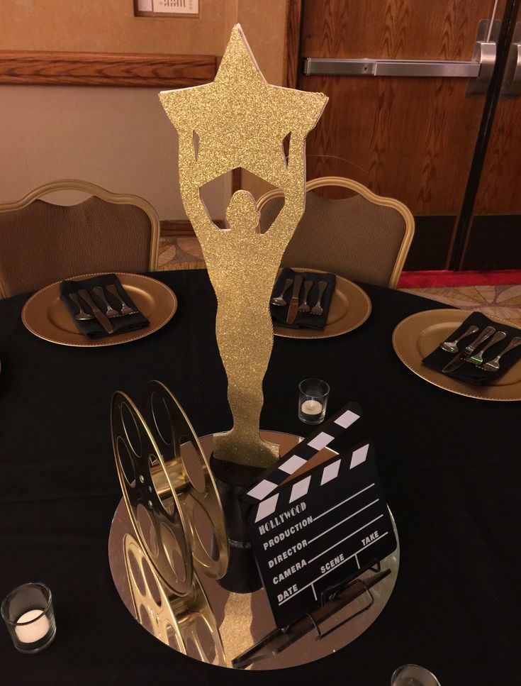 a black table topped with gold plates and silverware next to a star award trophy