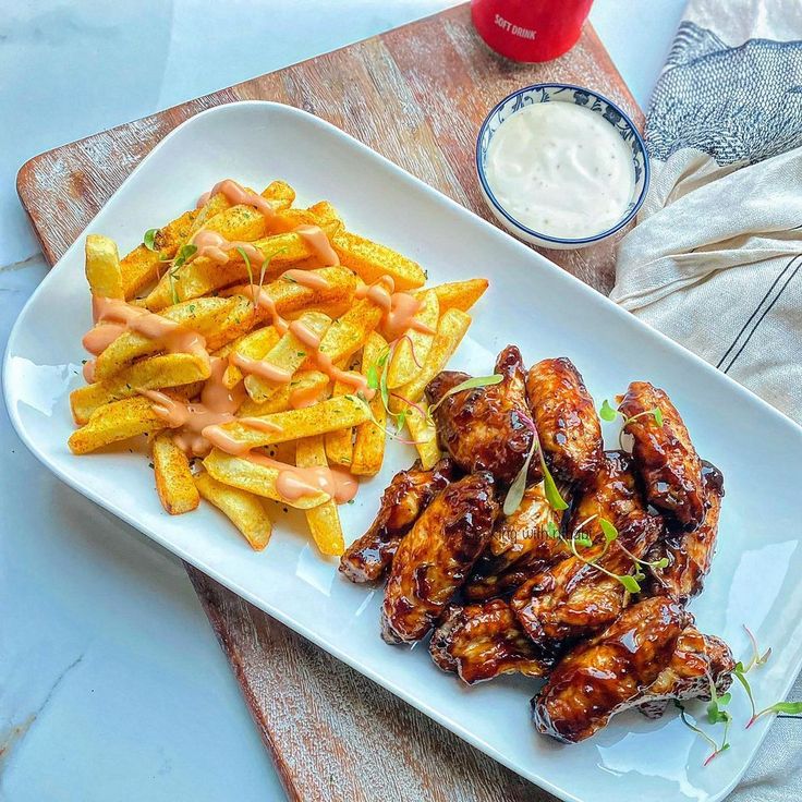 a white plate topped with chicken wings and fries