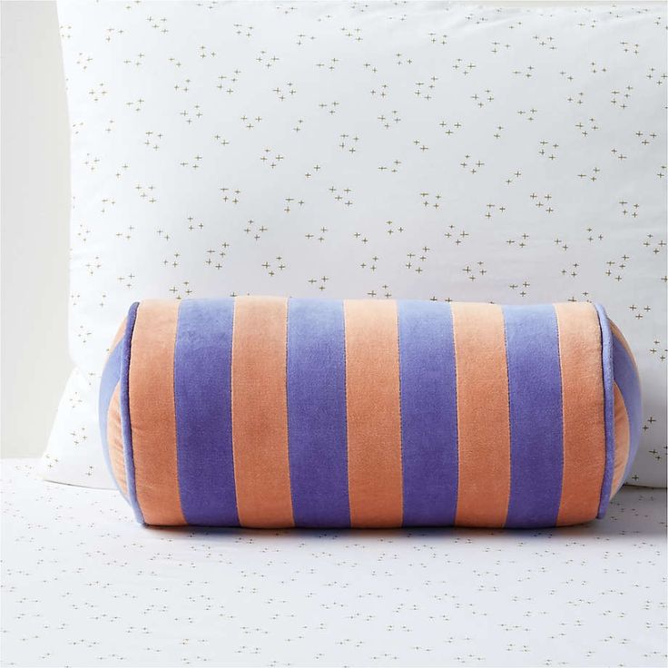 an orange and purple striped pillow sitting on top of a bed