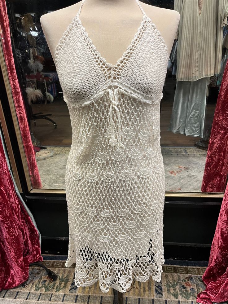 a mannequin wearing a white crochet dress in front of a store window