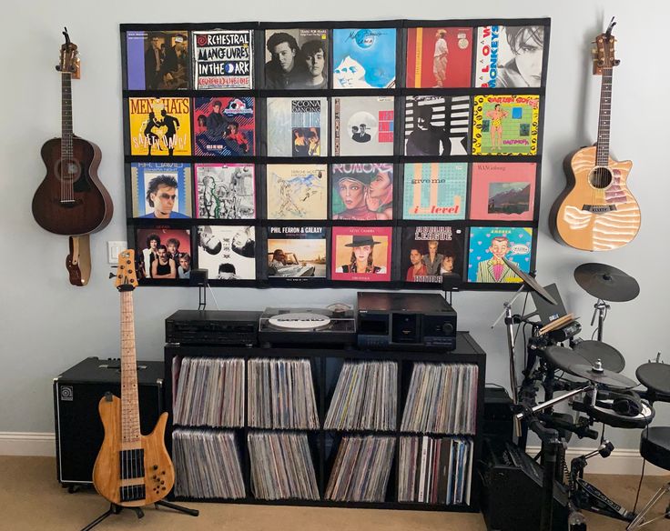 a room filled with musical instruments and record player's equipment in front of a wall full of records