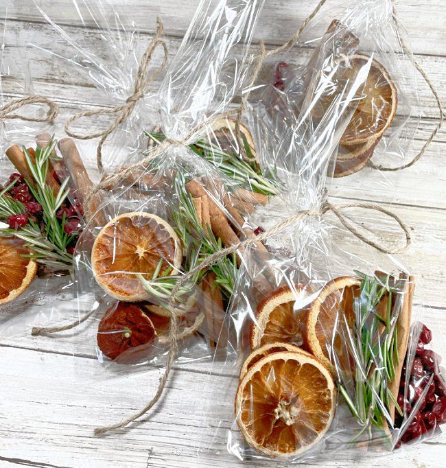 dried oranges and rosemary are wrapped in clear cellophane on a white wooden surface