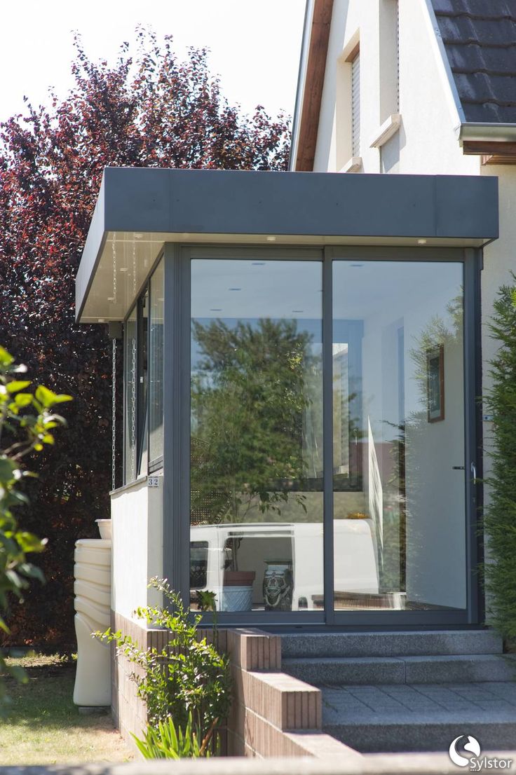 a house with glass walls and steps leading up to the front door