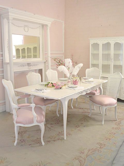 a dining room with pink walls and white furniture