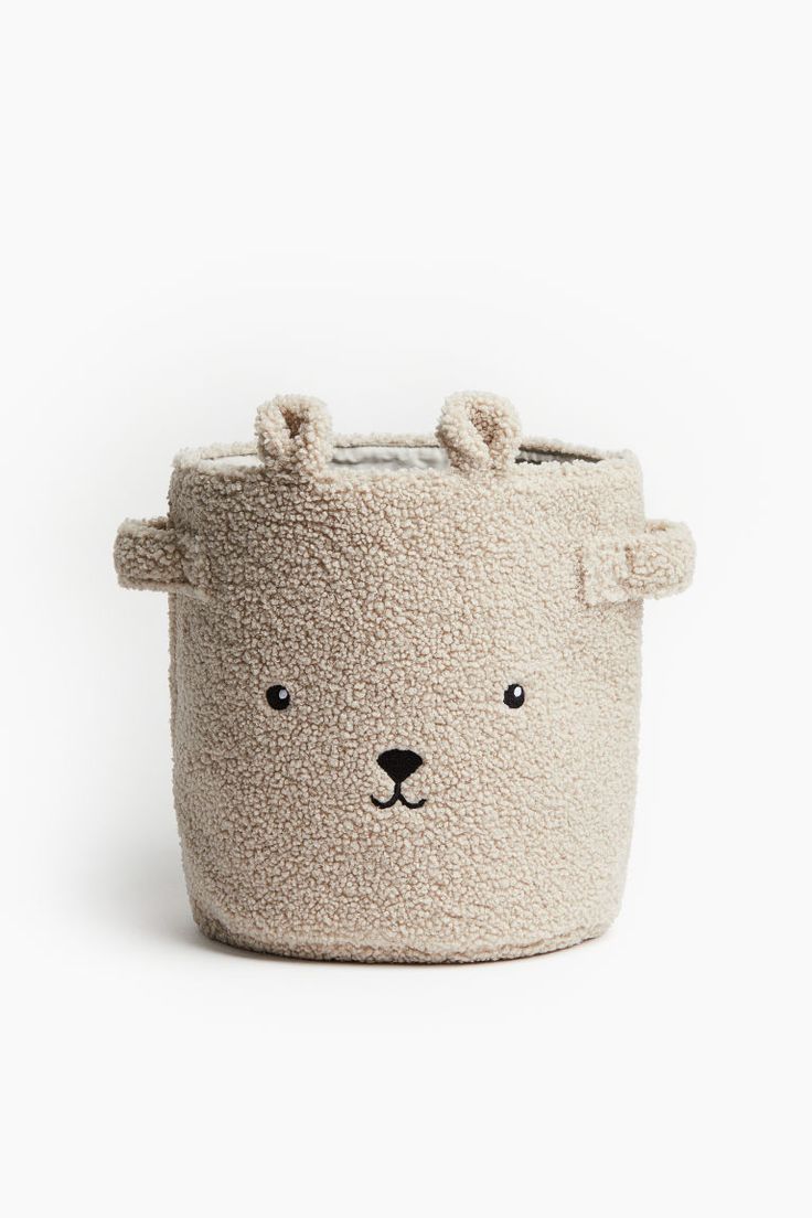 a small stuffed animal toy in a white basket with ears on it's head