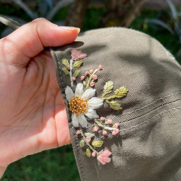 someone is stitching flowers on the side of a hat