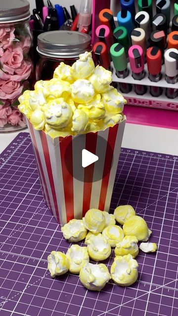 a popcorn bucket filled with yellow and white marshmallows on top of a purple cutting board