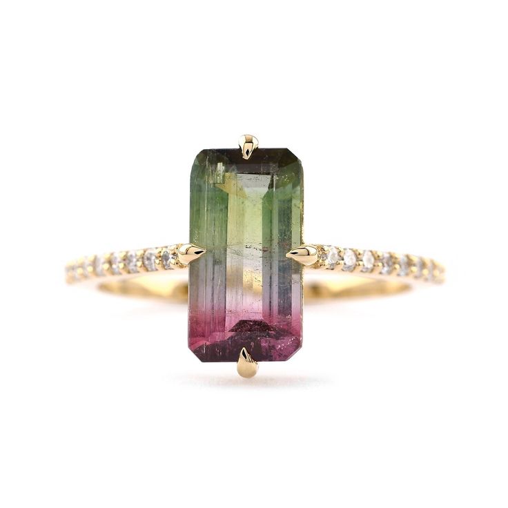 an emerald and pink tourmaline ring with diamonds on the band, set in yellow gold