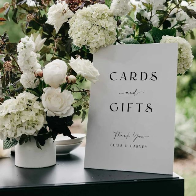 cards and gifts are sitting on a table with flowers in vases next to it