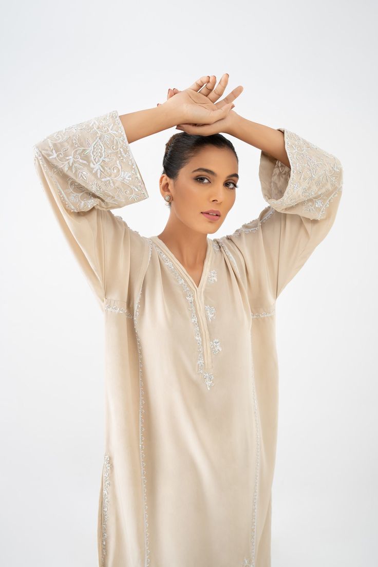 Introducing an exquisite ensemble consisting of a medium-length shirt in a pristine ivory shade, made from pure crepe silk. The shirt is meticulously handworked in self shades, featuring delicate details of resham, kora, and sequins throughout. The front and back of the shirt are fully adorned with this intricate work. To complete the ensemble, it is paired with a matching skinny shalwar, which also features matching work on the bottom. Hand Embellished Long Sleeve Blouse, Elegant Embellished Raw Silk Kurta, Elegant Festive Blouse With Dabka Work, Elegant Georgette Blouse Piece For Eid, Hand Embellished Long Sleeve Blouse For Wedding, Elegant Wedding Blouse With Dabka Work, Elegant White Long Sleeve Embroidered Top, Elegant Blouse With Dabka Work For Wedding, Elegant Georgette Blouse With Intricate Embroidery