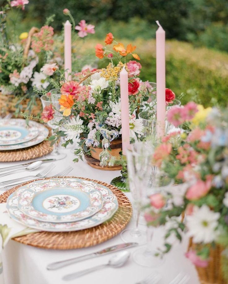 the table is set with plates and flowers in vases, candles and napkins