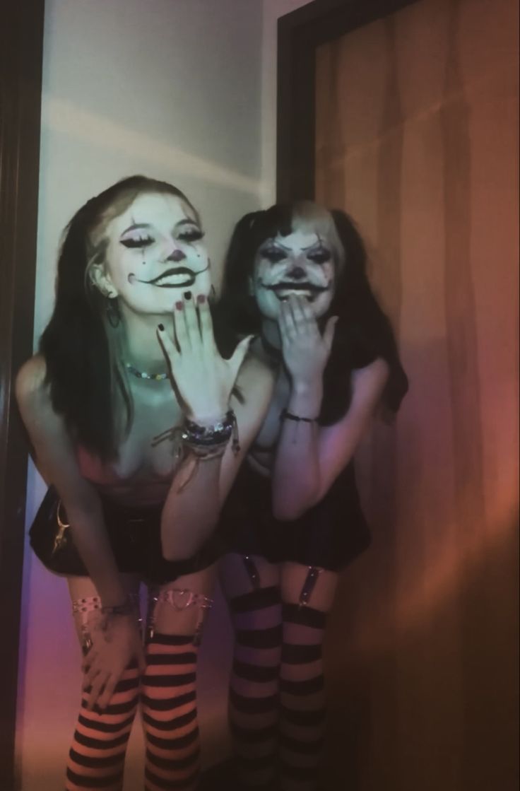 two women with painted faces posing in front of a mirror