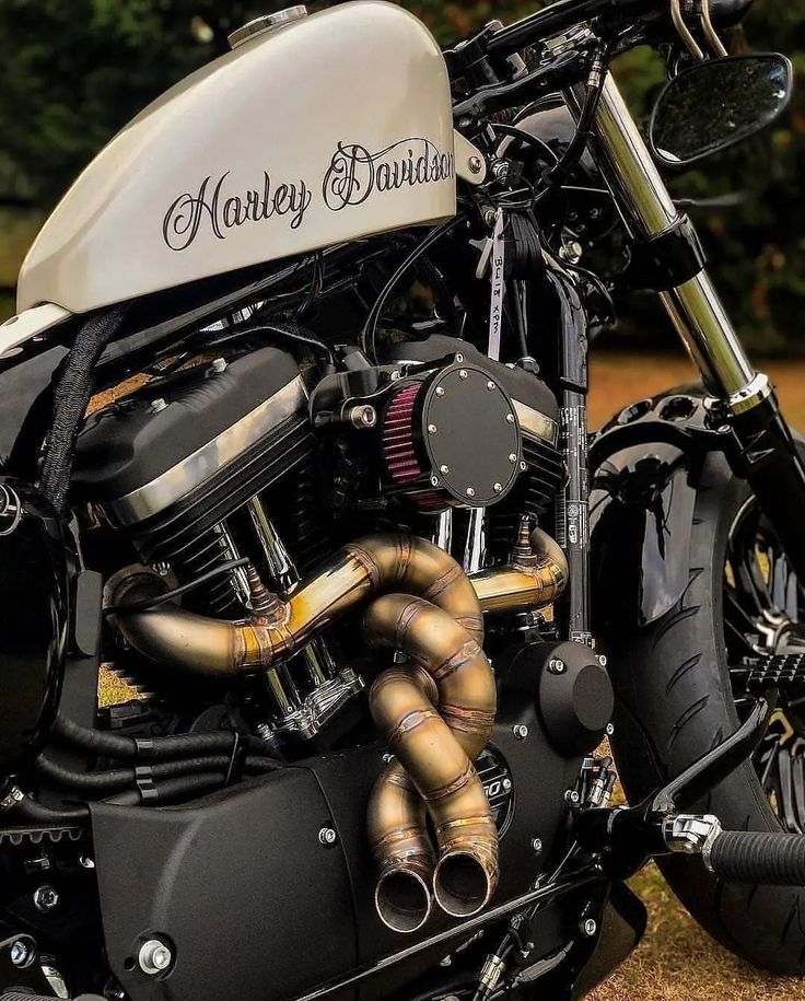 a close up of a motorcycle parked on the side of a road with trees in the background