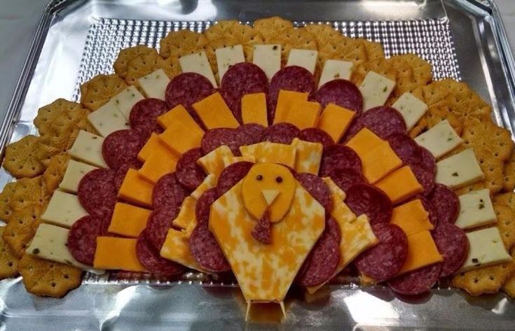 a turkey shaped cheese and cracker platter with meats on it's sides