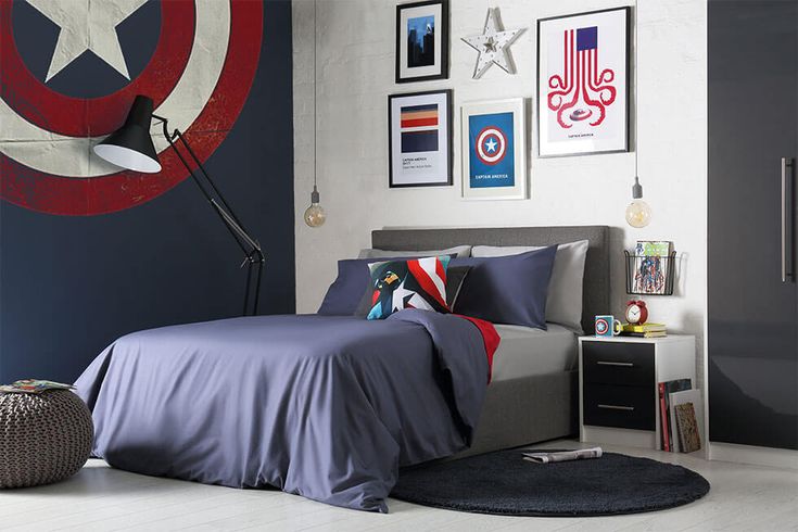 a bedroom with captain america decorations on the wall and bed in the center, along with pictures above it