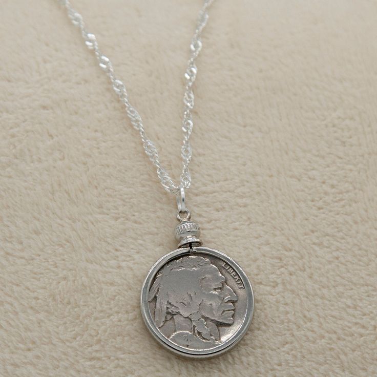 Introducing our exquisite Buffalo/Indian Head Nickel Necklace, a must-have accessory for history buffs, coin collectors, and vintage coin enthusiasts. This timeless piece effortlessly complements both casual and formal wear, making it a versatile addition to your jewelry collection. Featuring an authentic antique Buffalo Nickel from the early 1900s, each necklace tells a unique story of the past. Choose between our sophisticated 18-inch black cord or our elegant 20-inch silver plated braided rope chain, allowing you to customize the necklace to your personal style. Rest assured, every coin used in our necklaces is carefully cleaned before assembly, retaining the coin's original authenticity while enhancing its visual appeal. The bezel mount not only adds a touch of elegance but also serves Collectible Round Coin Pendant Jewelry, Antique Medallion Jewelry With Coin Pendant, Heirloom Coin Pendant Collectible Jewelry, Classic Round Coin Pendant Necklaces, Classic Coin Pendant Necklace, Classic Round Coin Pendant Necklace, Collectible Medallion Jewelry With Coin Pendant, Classic Coin Jewelry For Commemoration, Heirloom Nickel-free Jewelry For Collectibles