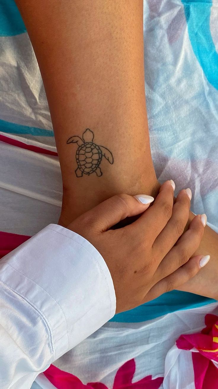 a woman's arm with a small turtle tattoo on her left wrist and right hand