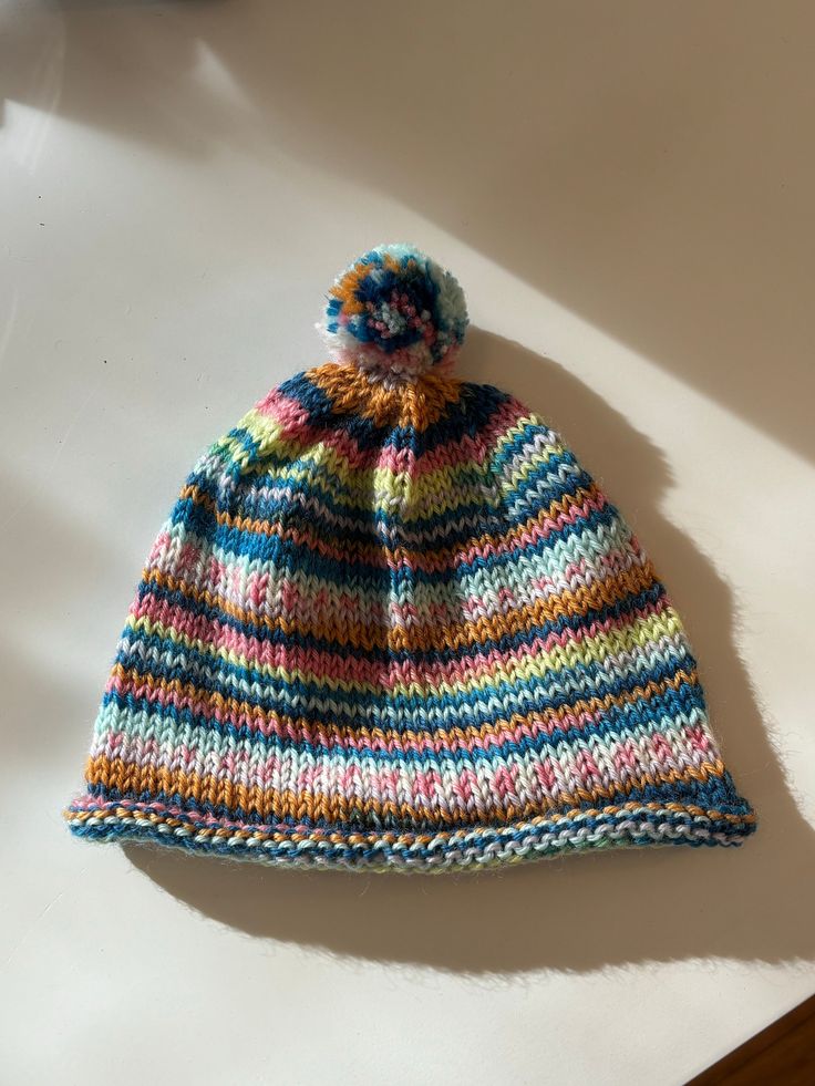 Colorful wool baby hat with pompom that brightens any coat! Cute Multicolor One-size Hats, Multicolor Hats For Playtime, One Size Fits Most, Playful Hats For Cold Weather, Playful Warm Hat For Playtime, Playful Multicolor Winter Beanie, Playful Multicolor Warm Beanie, Multicolor Playtime Hat, Cute Multicolor Hand-knitted Crochet Hat, Cute Multicolor Hand Knitted Crochet Hat