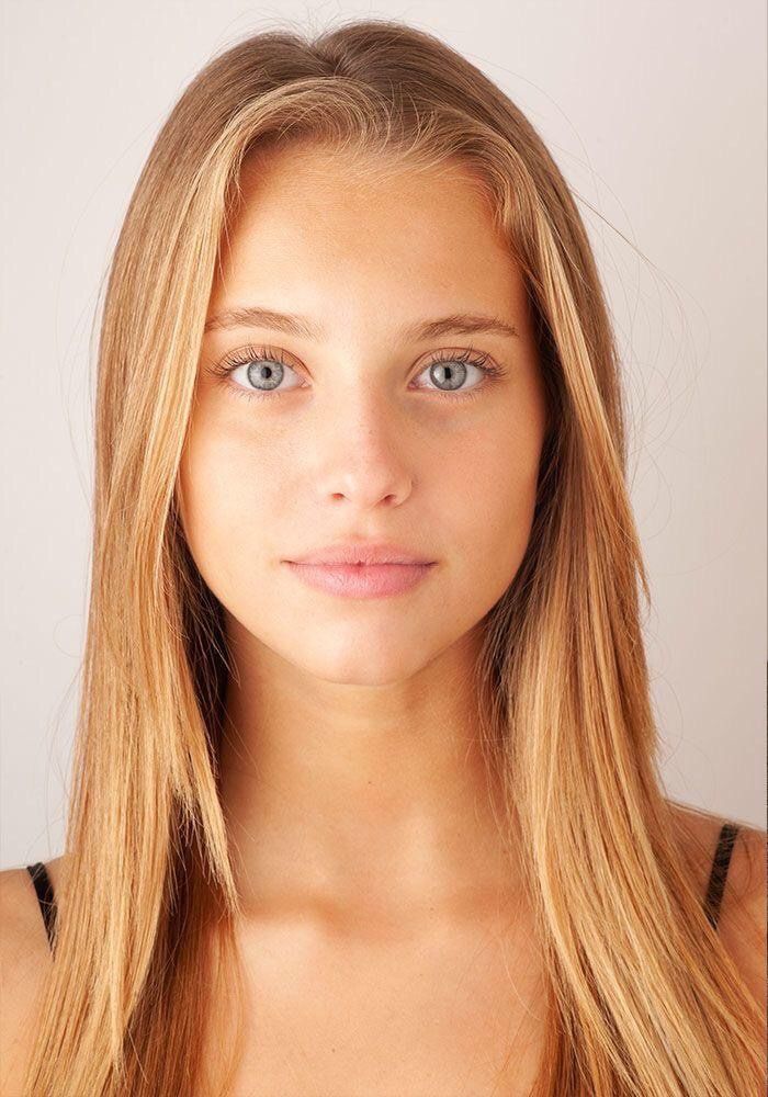 a woman with long blonde hair and blue eyes looking at the camera while wearing a tank top