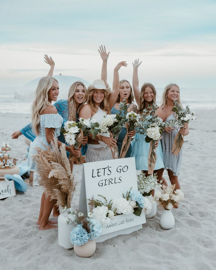 a group of women standing next to each other on top of a sand covered beach